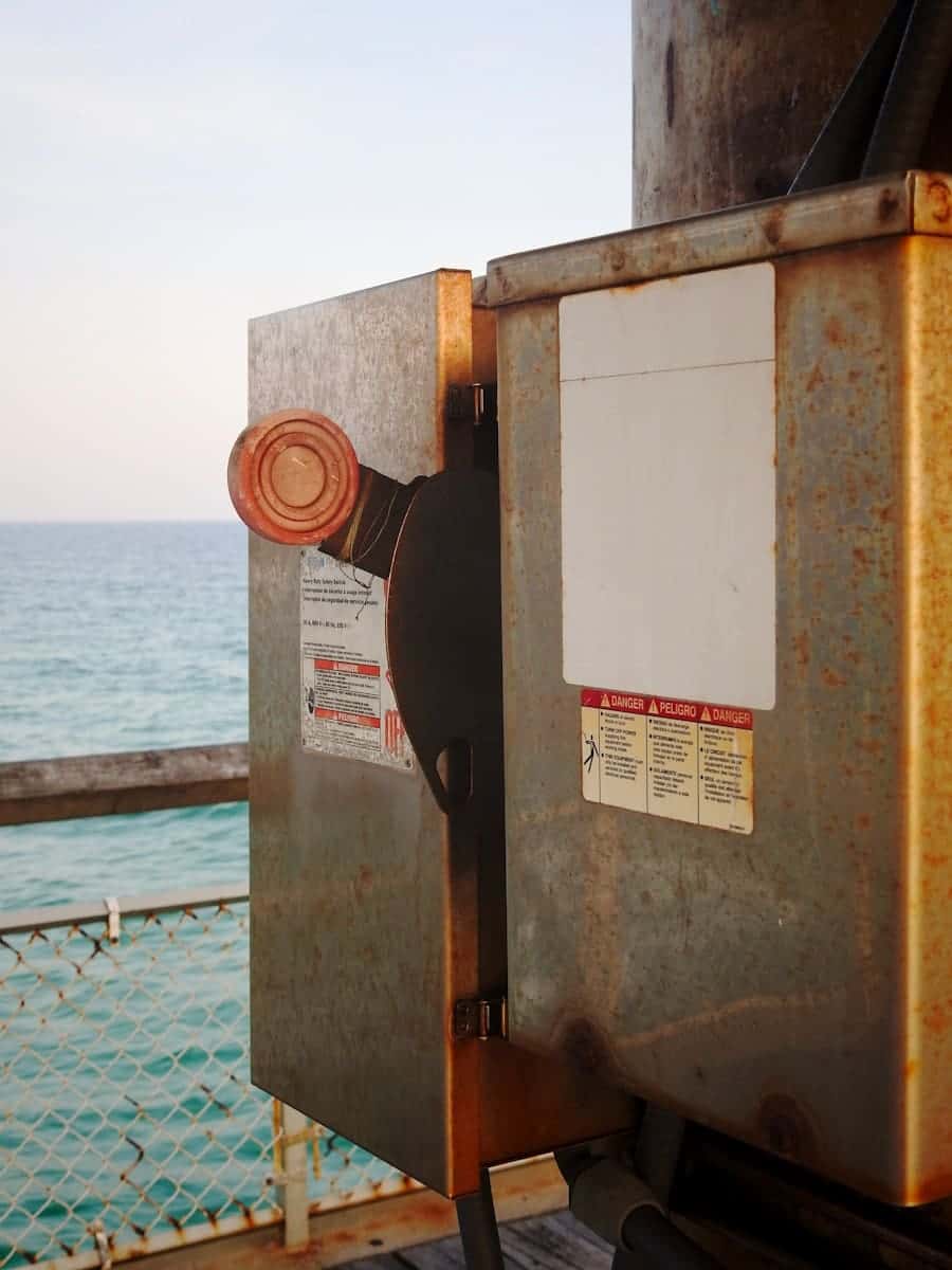 a close up of a rusted metal box near a body of water