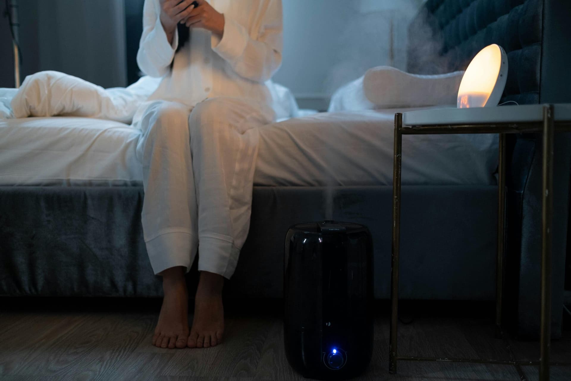 A serene bedroom scene with humidifier mist illuminating soft lighting, creating a calm atmosphere.