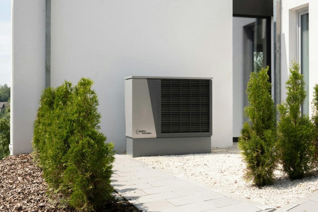 Top Air Heat Pumps for Efficient Heating 15 Outdoor air conditioner unit on a modern building surrounded by greenery and landscaping.