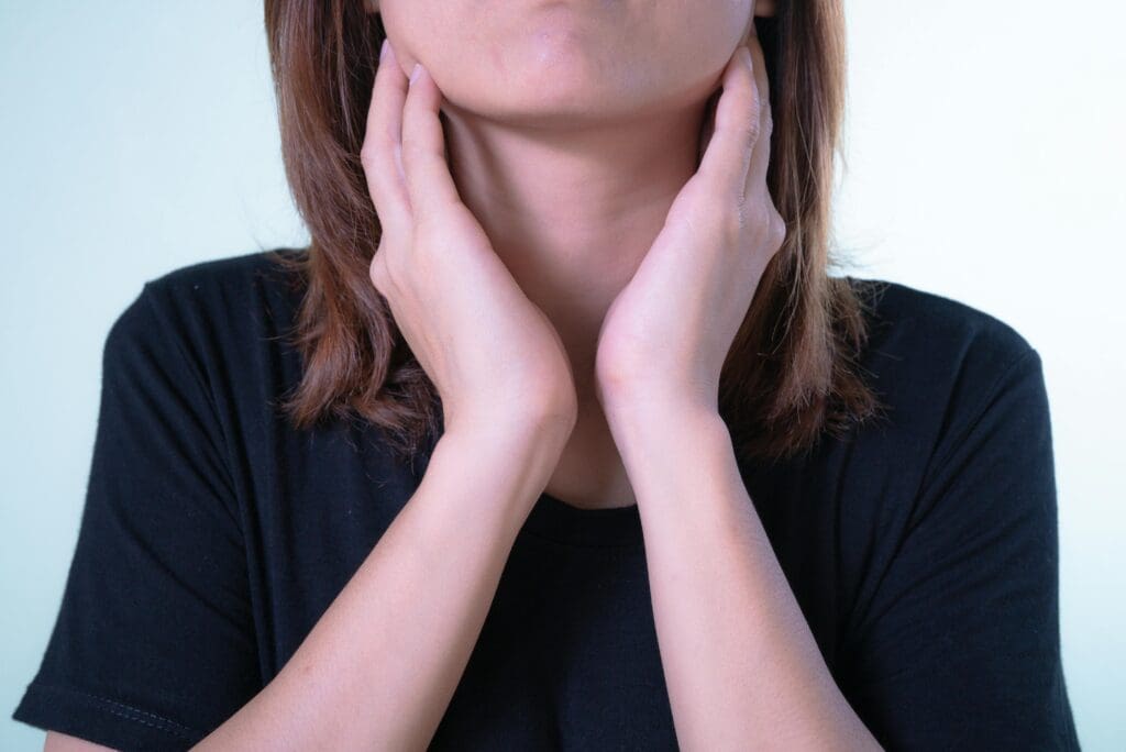 can dry air cause sore throat from air conditioner 104 Close-up of a woman touching her neck, possibly indicating discomfort or throat pain.