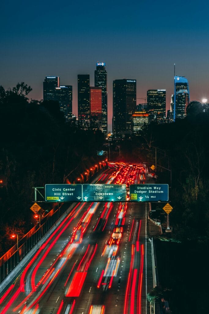 pexels-photo-2932436-2932436 Dynamic Los Angeles skyline at night with light trails on the freeway showcasing urban energy.