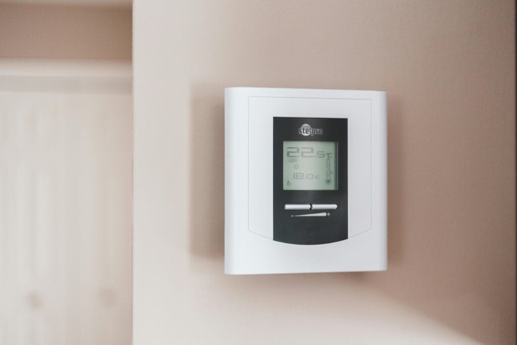 How to Fix AC Not Cooling Properly 267 Close-up of a modern digital thermostat mounted on a wall, displaying temperature settings in Celsius.